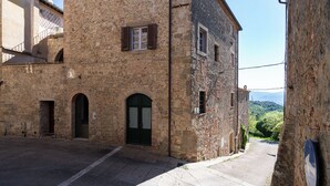 Una calle estrecha con edificios de piedra, puertas en arco y una vista despejada del paisaje circundante.