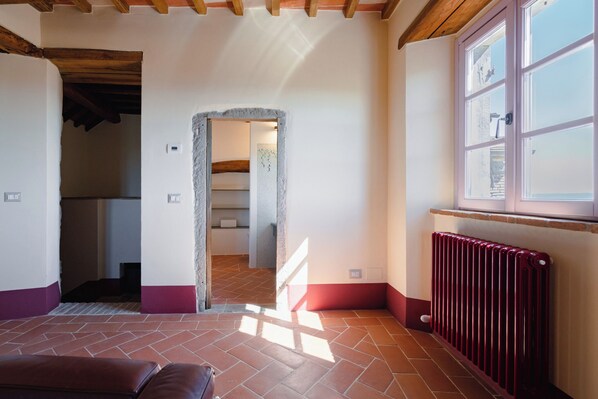 A room with a tiled floor, a window with a view, a radiator, and a doorway leading to another room. - Mensano Old Town Apartment (Mensano)