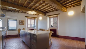 Una cocina con una isla grande, vigas de madera y un suelo con patrón de espiga.