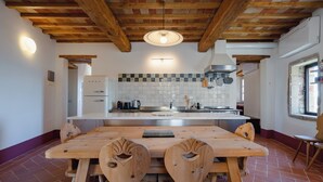 Una cocina con una mesa y sillas de madera, un salpicadero de azulejos y una lámpara colgante.