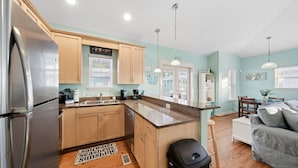 A modern kitchen with wooden cabinets, a stainless steel refrigerator, a sink, and a dining area with a table and chairs. - Pet-Friendly PCB Vacation Rental | Pool | Walk to Beach (Panama City Beach)
