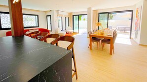 A modern dining area with a marble table, wooden chairs, and a large window offering a view of the outdoors.
