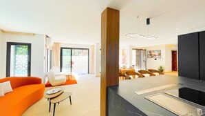A modern hotel lobby with a seating area, a dining table, and a black marble reception desk.