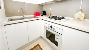 A modern kitchen with white cabinets, a stainless steel sink, a gas stove, and an oven. - Petit Cocon Neuf et Styl la Marsa (La Marsa)