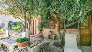 An outdoor seating area with wooden furniture, a stone wall, and olive trees. - Nice home in Ragusa with house a panoramic view (Ragusa)