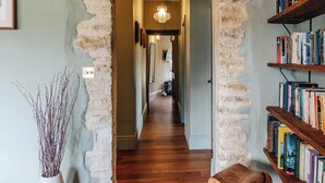 A hallway with a stone archway, wooden flooring, a bookshelf, and a vase with branches. - NEW luxury historic apartment, private garden, parking, dog-friendly, in Tetbury (Tetbury)