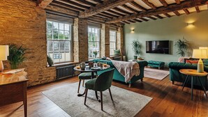 A cozy living room with a dining area, large windows, and a television. - NEW luxury historic apartment, private garden, parking, dog-friendly, in Tetbury (Tetbury)