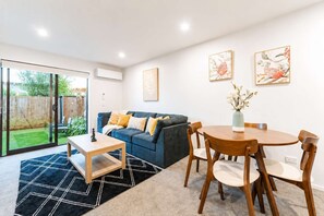 A modern living room with a sofa, coffee table, and dining table. - 2BR Christchurch Stay | Near CBD, Hagley & Stadium (Christchurch)