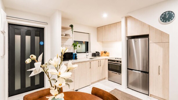 Una cocina moderna con una isla central, electrodomésticos de acero inoxidable y armarios de madera clara.