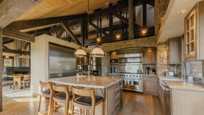 Une cuisine spacieuse dotée d’un grand îlot central, de tabourets de bar en bois et d’appareils électroménagers modernes.