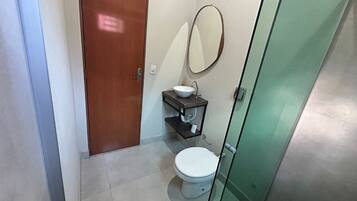 A small bathroom with a toilet, a sink, and a mirror.