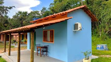 A small, single-story building with a tiled roof, a window, and an air conditioning unit.