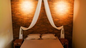 Een bed met hemel in een kamer met bakstenen muren.