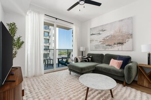 Relax in this stylish living room with a large flat-screen TV, plush sofa, and a round coffee table.