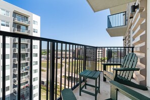 Enjoy the view from this apartment's balcony, featuring a comfortable seating area with two Adirondack chairs and a small table.