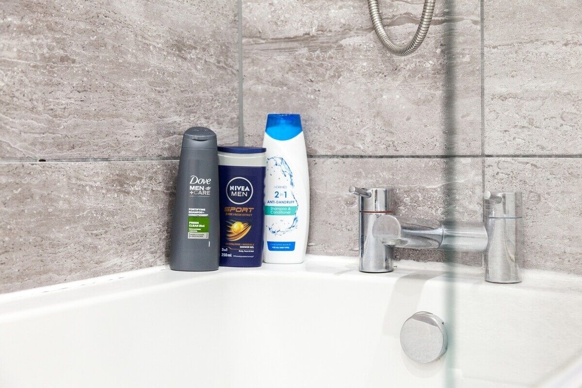 Ein Badezimmer mit einem weißen Waschbecken, zwei Flaschen Dove Men+Care Duschgel und einem Nivea Men+Care Shampoo.