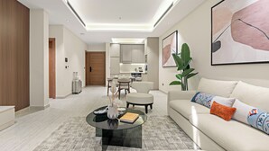 A modern living room with a sofa, coffee table, and a dining area in the background. - LIV by Yamama - KAFD (Riyadh)