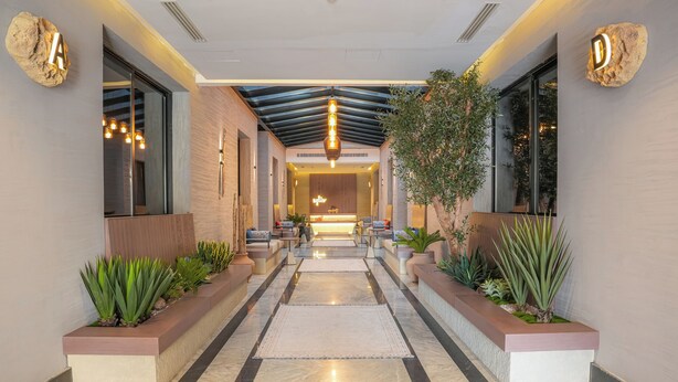A modern hotel lobby with a central seating area, a reception desk, and potted plants along the walkway. - LIV by Yamama - KAFD (Riyadh)