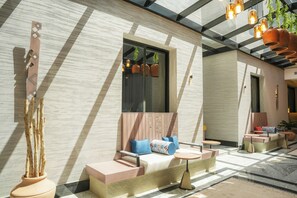 A modern outdoor seating area with a cushioned bench, a small table, and a decorative vase. - LIV by Yamama - KAFD (Riyadh)