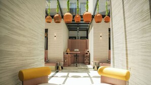 A modern interior with a kitchen area, two yellow cushioned seating areas, and hanging terracotta pots. - LIV by Yamama - KAFD (Riyadh)