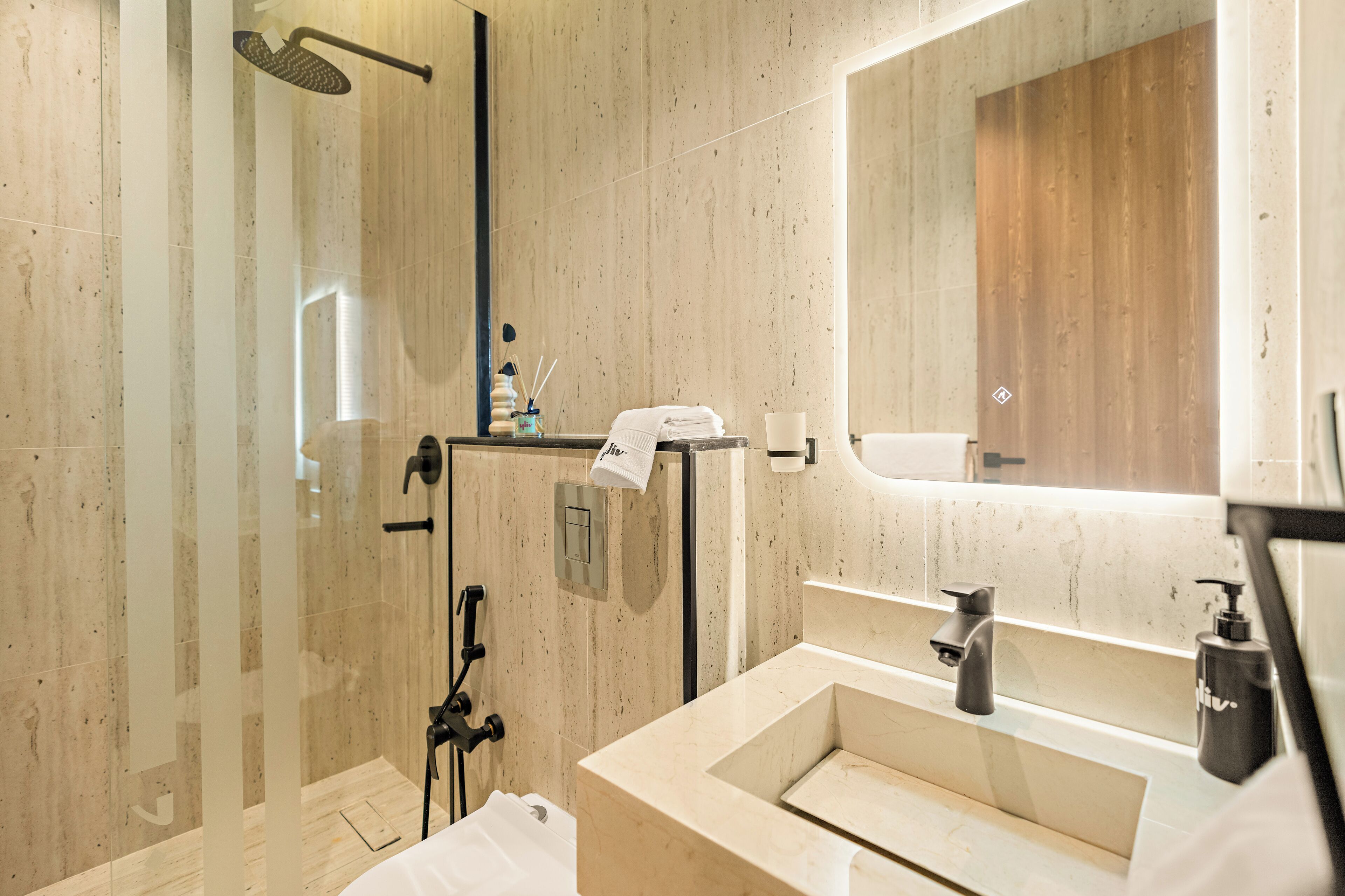 A modern bathroom with a glass-enclosed shower, a large mirror, and a vanity with a sink and faucet.