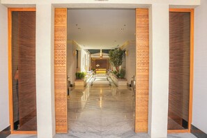 A hotel lobby with a marble floor, patterned wooden panels, and a central seating area. - LIV by Yamama - KAFD (Riyadh)