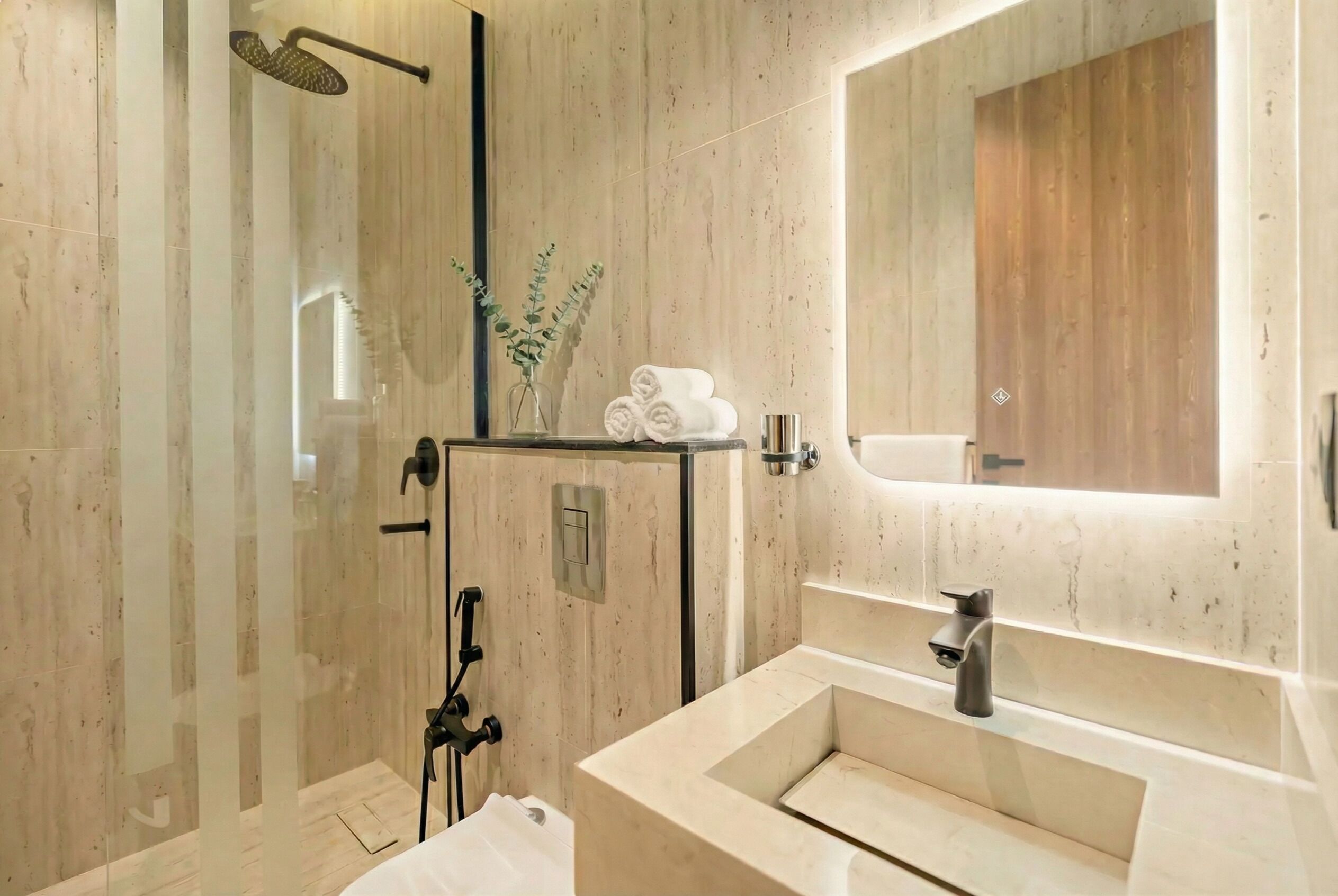 A modern bathroom with a glass-enclosed shower, a large mirror, and a beige sink.