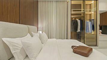 Una habitación de hotel moderna con una cama grande, ropa de cama blanca, un bolso marrón y un vestidor con ropa colgada.