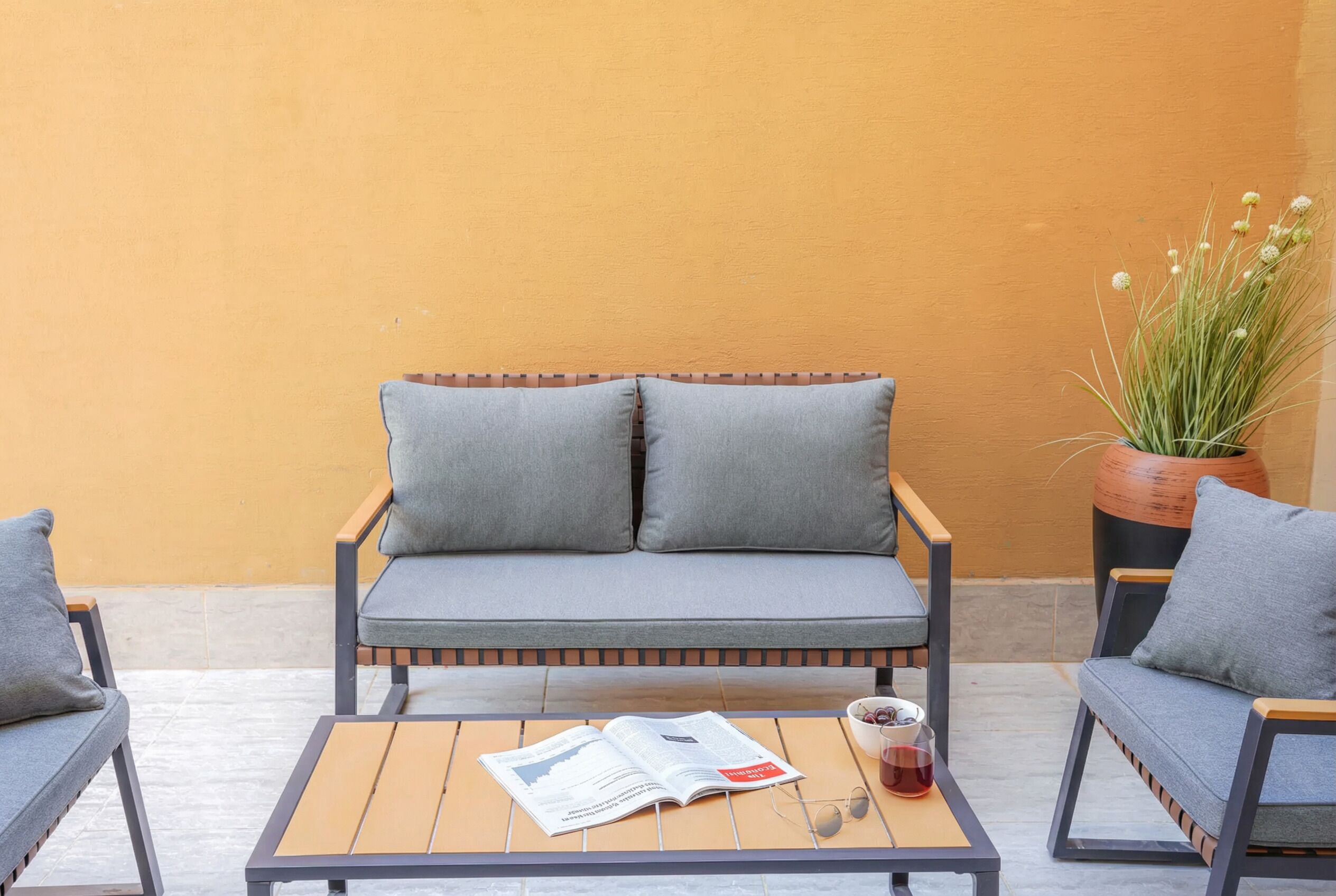 Un sofá con cojines, una mesa con una revista, una taza y una planta en maceta.