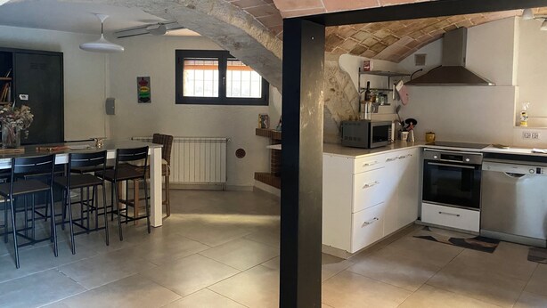 Eine Küche mit Herd, Mikrowelle und einem Fenster. Es gibt einen Essbereich mit Stühlen und einem Tisch.