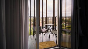 A balcony with a table and chairs, a view of the cityscape, and a door with curtains. - Modern 1BR - Balcony - in Center by Torro Mall (Chișinău)