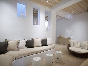 Uma sala de estar moderna com um sofá, uma poltrona redonda de vime e um armário.