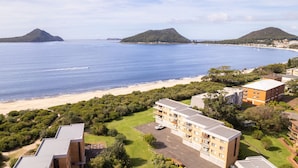 A coastal hotel with multiple buildings, a beach, and mountains in the background.