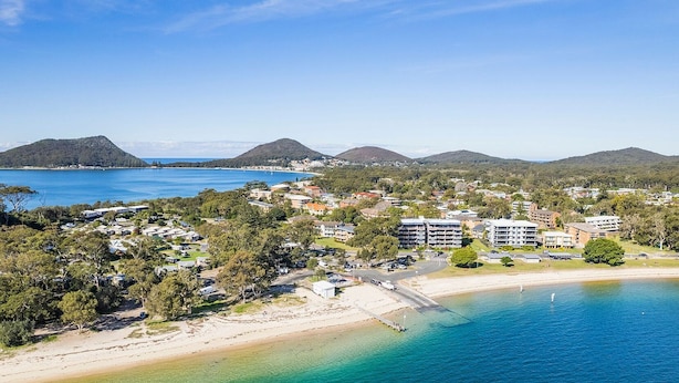 A coastal town with beachfront properties, a marina, and a hilly backdrop.