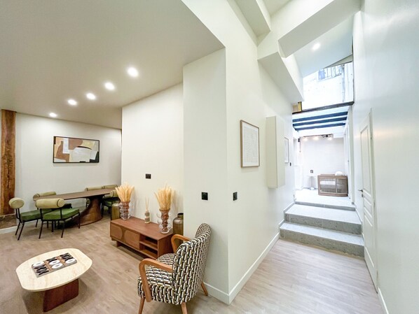 A modern living room with a dining area, a staircase leading to an upper level, and a view of the outside.