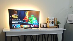 A flat-screen TV on a white table with a black metal frame. - BREEZE RESIDENCES MANILA BAY VIEW (Pasay)