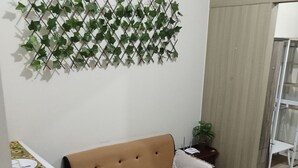 A living room with a sofa, a coffee table with drinks, a small plant, and a dining area with a table set for two. - BREEZE RESIDENCES MANILA BAY VIEW (Pasay)