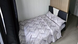 A bedroom with a bed, a wooden headboard, and a curtain. - BREEZE RESIDENCES MANILA BAY VIEW (Pasay)