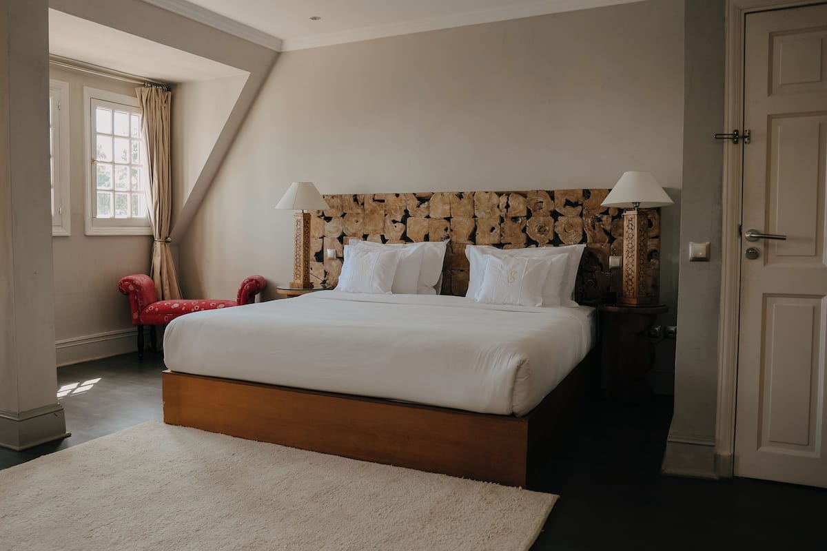Ein Schlafzimmer mit einem großen Bett, einem roten Sessel und einem Holz-Kopfteil.