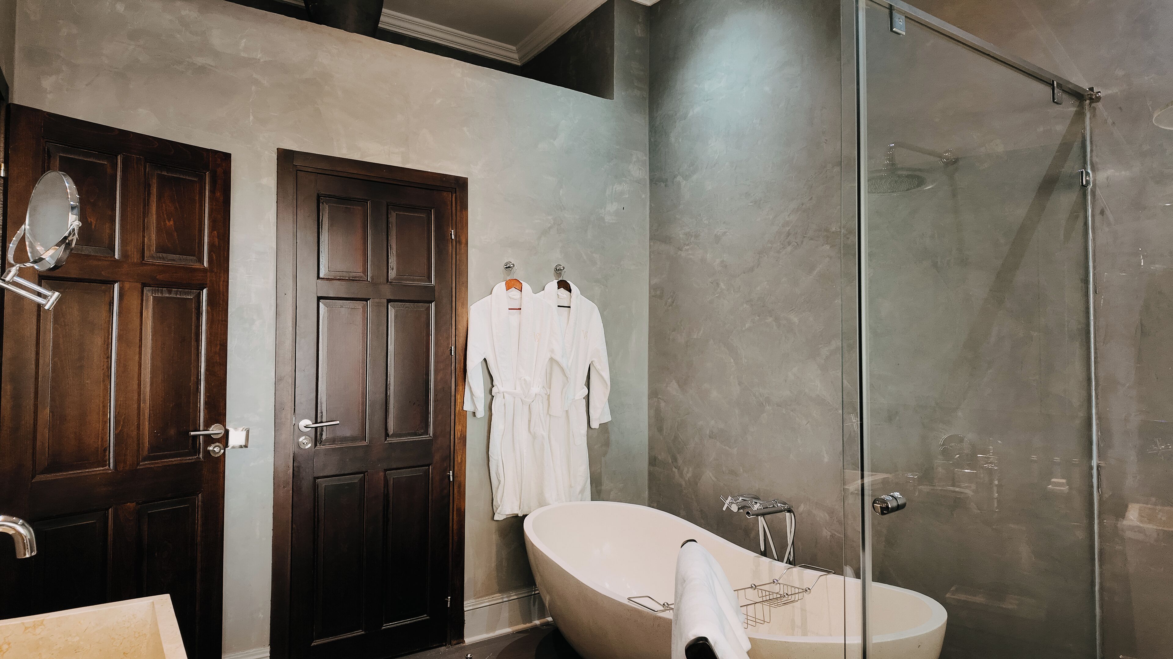 Un baño con una puerta de madera oscura, una bañera blanca y una cabina de ducha de vidrio.