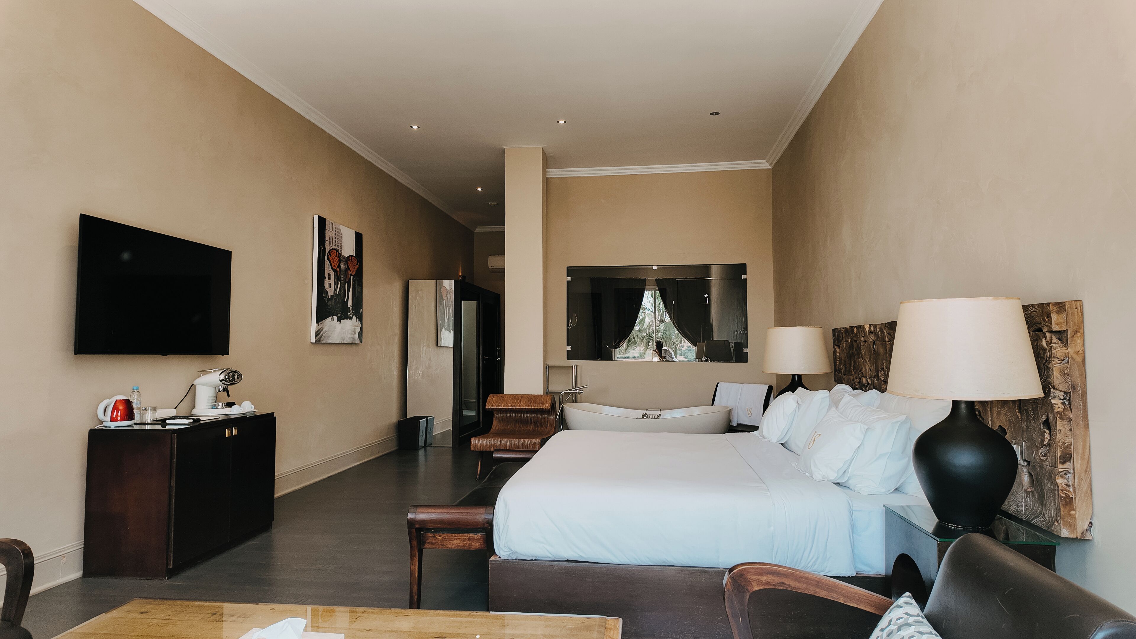 A hotel room with a bed, a desk, a television, a mirror, and a bathroom.