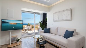 A modern living room with a sofa, a coffee table, a TV, and a balcony with a view of the sea. - Evilion Home 2 (Agios Nikolaos)