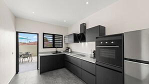 A modern kitchen with black appliances, a dining area with chairs, and a view through a window.