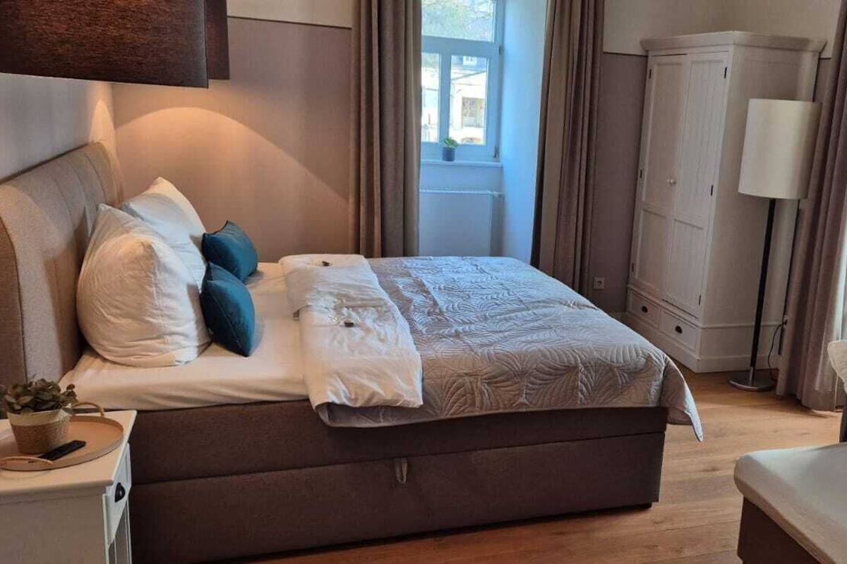 A bedroom with a large bed, bedside tables, a wardrobe, and a window with curtains.