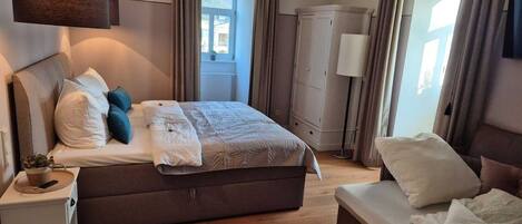 A bedroom with a large bed, bedside tables, a wardrobe, and a window with curtains.