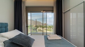A hotel room with a bed, a view of a landscape through a large window, and a sliding door.