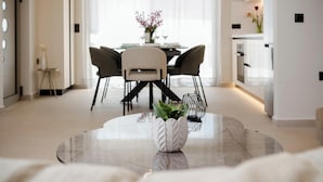 A modern dining area with a round table, chairs, and a potted plant.