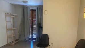 Una habitación moderna y luminosa con una cama, una mesita con un florero, dos sillas y una escalera contra la pared.