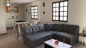 Una sala de estar con un sofá modular, una mesa de centro y un comedor con una mesa y sillas.