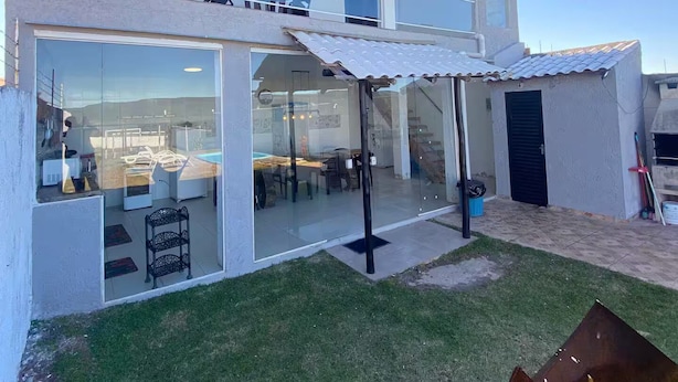 Una casa de dos pisos con un patio acristalado, un comedor y un pequeño jardín.